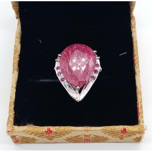 439 - A sterling silver ring with a large pear cut ruby surrounded by a silver halo with nine small rubies... 