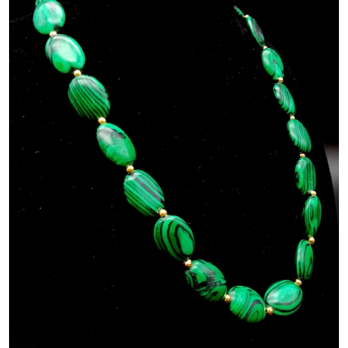 656 - A Malachite Flat Oval Bead Necklace with Gold Spacers and Clasp. 44cm.