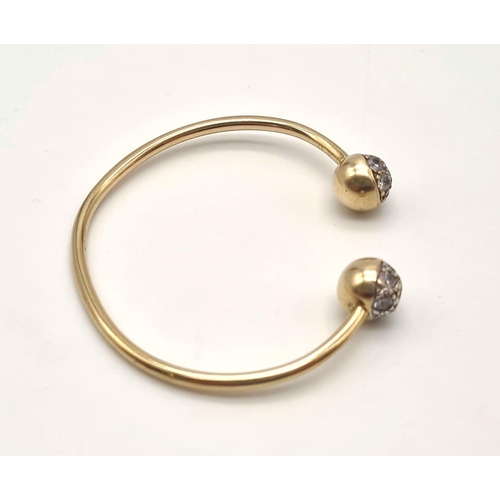 443 - A 9K Yellow Gold Childs Bangle with White Stone Decoration. 6.25g total weight. Ref - 3298