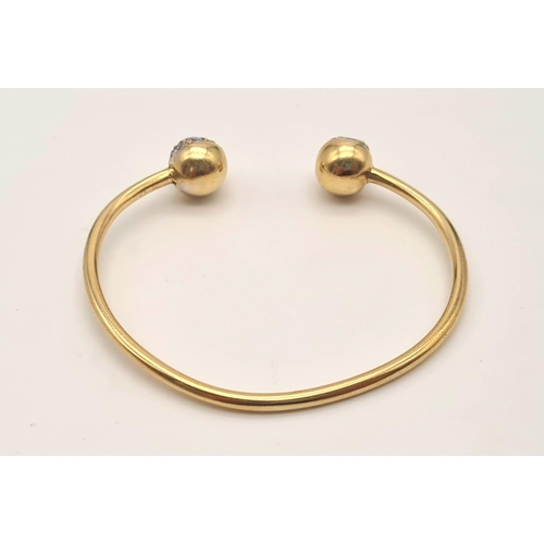 443 - A 9K Yellow Gold Childs Bangle with White Stone Decoration. 6.25g total weight. Ref - 3298