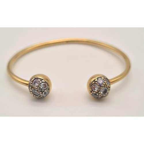 443 - A 9K Yellow Gold Childs Bangle with White Stone Decoration. 6.25g total weight. Ref - 3298