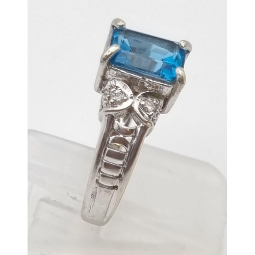 725 - A 9K White Gold Topaz Diamond Ring. Central topaz with two diamonds either side. 1ct - topaz. .2ct -... 