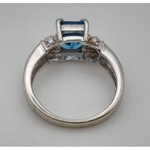 725 - A 9K White Gold Topaz Diamond Ring. Central topaz with two diamonds either side. 1ct - topaz. .2ct -... 