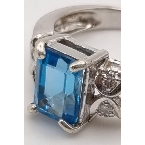 725 - A 9K White Gold Topaz Diamond Ring. Central topaz with two diamonds either side. 1ct - topaz. .2ct -... 