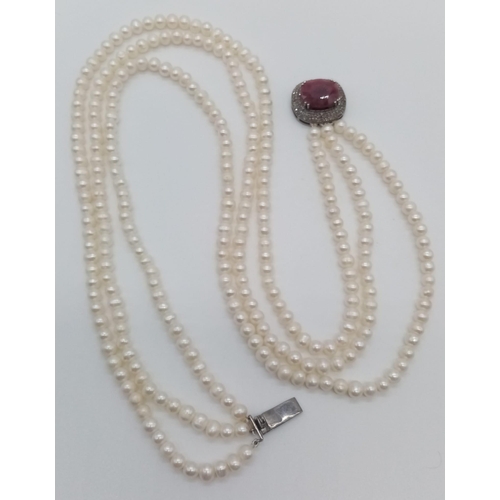 132 - A wonderful vintage three strand natural pearl necklace with a silver clasp with central oval cut ru... 