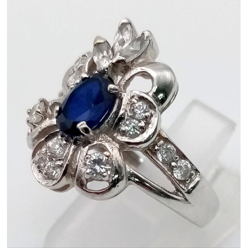 519 - 18K Gold Sapphire & Diamond Ring. Central sapphire surrounded by petals of diamonds. Size O. 5.32g t... 