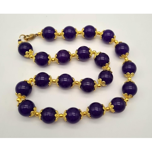 732 - A Purple Jade Beaded Necklace. Gilded spacers and clasp. Beads - 12mm. 44cm.