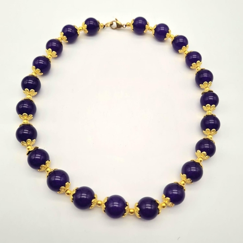 732 - A Purple Jade Beaded Necklace. Gilded spacers and clasp. Beads - 12mm. 44cm.