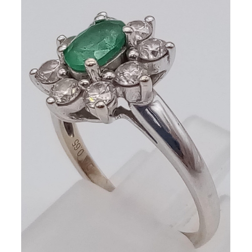 100 - An 18K White Gold Emerald and Diamond Ring. Central oval emerald - 0.5ct surrounded by eight petals ... 