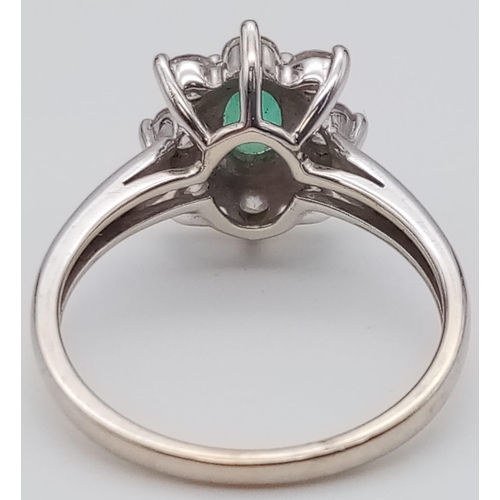 100 - An 18K White Gold Emerald and Diamond Ring. Central oval emerald - 0.5ct surrounded by eight petals ... 