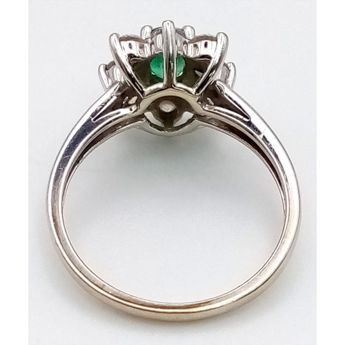 100 - An 18K White Gold Emerald and Diamond Ring. Central oval emerald - 0.5ct surrounded by eight petals ... 