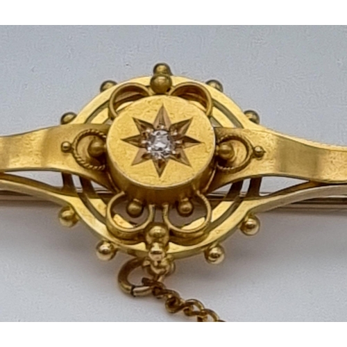 352 - AN EDWARDIAN SINGLE DIAMOND BAR BROOCH IN 15K GOLD WITH SAFETY CHAIN.  4.0gms