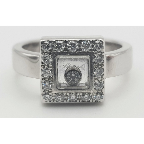 53 - An 18K White Gold Floating Diamond Ring. A square of diamonds shield a central floating diamond. Siz... 