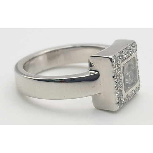 53 - An 18K White Gold Floating Diamond Ring. A square of diamonds shield a central floating diamond. Siz... 