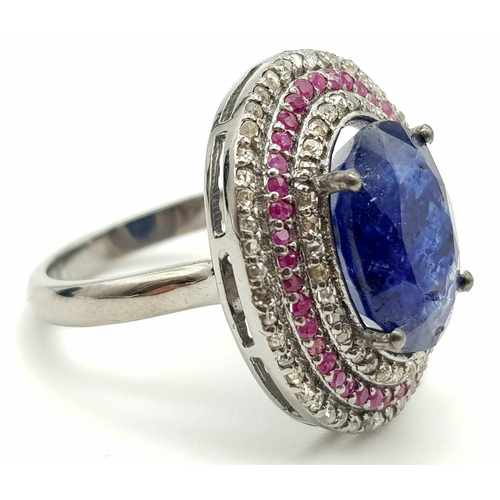 587 - 8.55ct Oval Cut Blue Sapphire ring with a halo of rubies and two rows of 1.25cts diamonds in a pave ... 