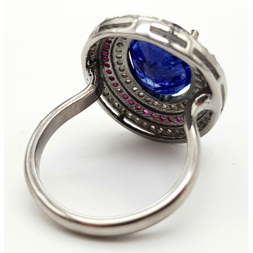 587 - 8.55ct Oval Cut Blue Sapphire ring with a halo of rubies and two rows of 1.25cts diamonds in a pave ... 