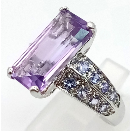 171 - A 9K White Gold Amethyst and Tanzanite Ring. Large clean central baguette-cut amethyst with eight ro... 