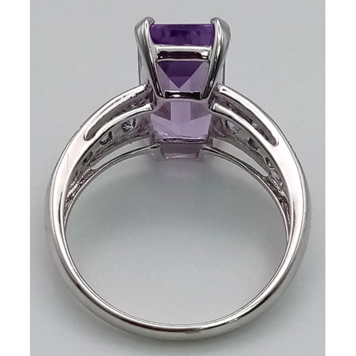 171 - A 9K White Gold Amethyst and Tanzanite Ring. Large clean central baguette-cut amethyst with eight ro... 