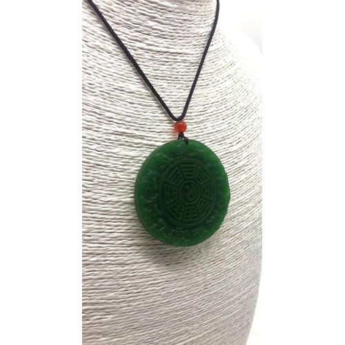 507 - A Green Jade Circular Pendant. Decorated with Chinese Lunar characters. 5cm diameter.