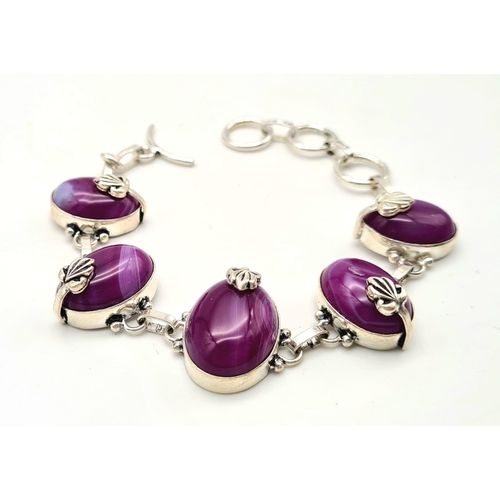 182 - A sterling silver bracelet with magenta coloured banded agate cabochons. In a presentation box. Leng... 