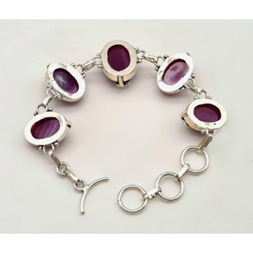 182 - A sterling silver bracelet with magenta coloured banded agate cabochons. In a presentation box. Leng... 