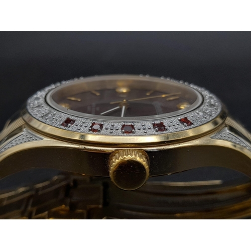 70 - A Gem Encrusted Ingersoll Quartz Watch. Gold plated strap and case - 40mm. Red and white gemstone en... 