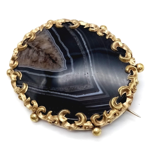 1104 - A Victorian Banded Agate Yellow Metal Brooch. Large agate slice with scrolled gilded attachment. 6x ... 