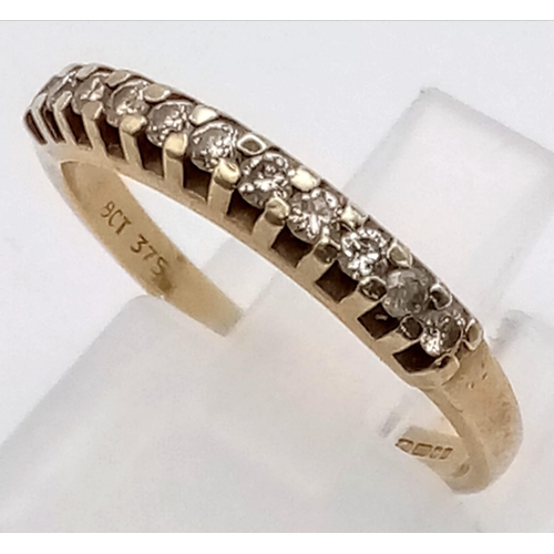 529 - A 9 K yellow gold ring with a band of eleven diamonds (0.15 carats). Ring size: M, weight: 1.6 g.