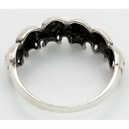 635 - A Solid Silver Six Skull Gents Ring. Z + 1. 5.7g