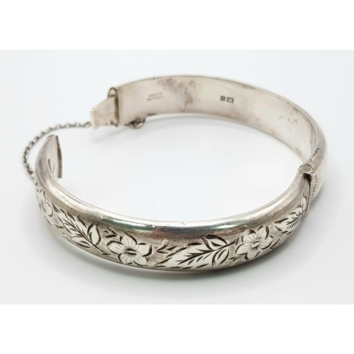 530 - A sterling silver hinged bangle with safety chain. Inner diameter 58 mm, weight: 21.3 g.