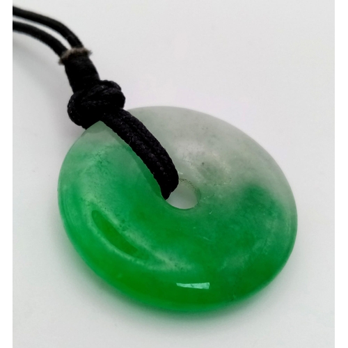 488 - A round shaped jade pendant on cord. Diameter: 32 mm.