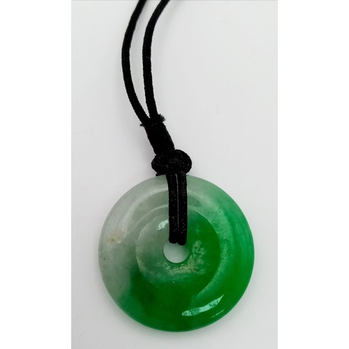 488 - A round shaped jade pendant on cord. Diameter: 32 mm.