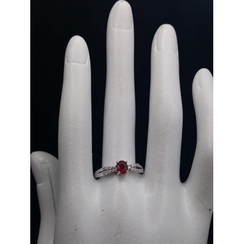 277 - A Beautiful, Understated 18K White Gold Ruby and Diamond Ring. A central oval clean faceted ruby wit... 