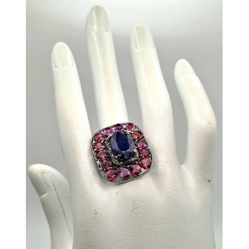 303 - A 5.75ct Blue Sapphire Ring with 5.30ct Rhodolite Gemstones set in 925 Silver. Size N. 11.26g total ... 