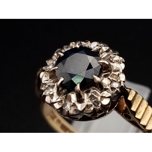 592 - A Vintage 9K Yellow Gold Sapphire and Diamond Ring. Central blue sapphire with an eight diamond halo... 