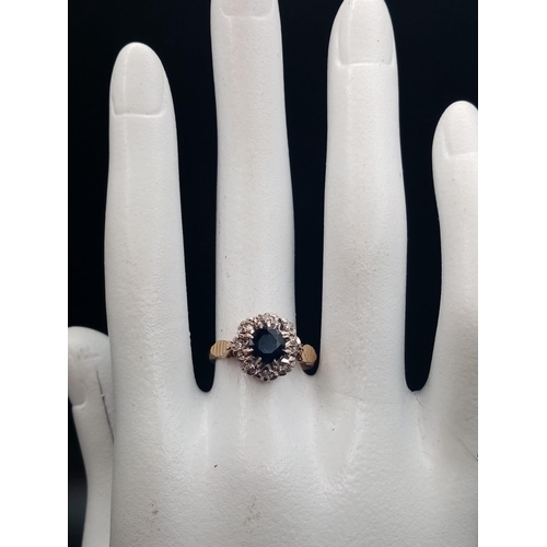 592 - A Vintage 9K Yellow Gold Sapphire and Diamond Ring. Central blue sapphire with an eight diamond halo... 