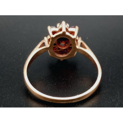 669 - A Vintage 9K Yellow Gold Garnet Ring. Central garnet oval stone surrounded by a halo of smaller garn... 