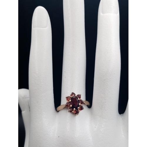 669 - A Vintage 9K Yellow Gold Garnet Ring. Central garnet oval stone surrounded by a halo of smaller garn... 