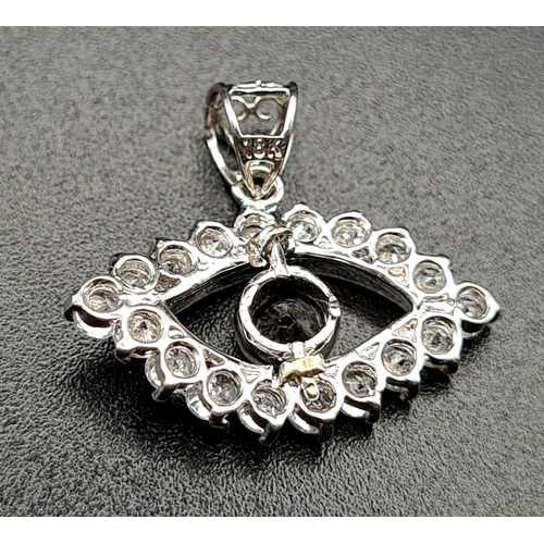 676 - An 18K White Gold Sapphire and Diamond Eye Pendant. Blue sapphire pupil surrounded by an outer eye-s... 