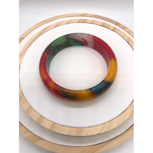 286 - A Multi-Coloured Jade Bangle. 6cm inner diameter.