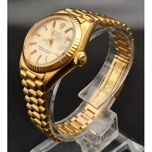 74 - An 18K Gold Rolex Oyster Perpetual Ladies Watch. Gold strap and case - 26mm. White dial with date wi... 