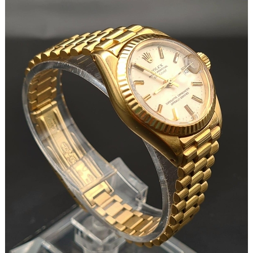 74 - An 18K Gold Rolex Oyster Perpetual Ladies Watch. Gold strap and case - 26mm. White dial with date wi... 