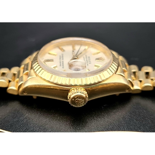 74 - An 18K Gold Rolex Oyster Perpetual Ladies Watch. Gold strap and case - 26mm. White dial with date wi... 