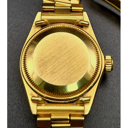 74 - An 18K Gold Rolex Oyster Perpetual Ladies Watch. Gold strap and case - 26mm. White dial with date wi... 