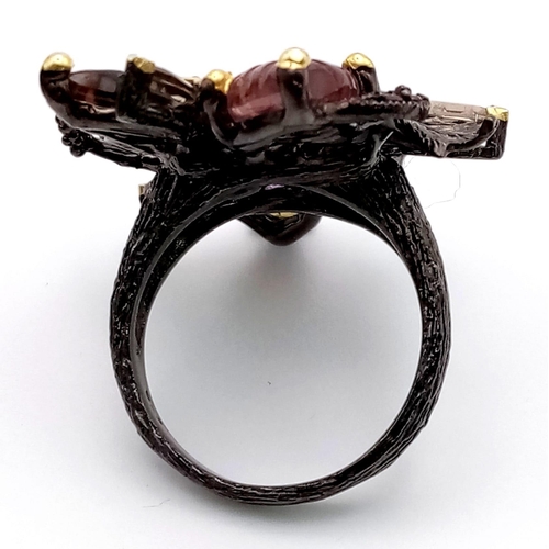 133 - An Edwardian sterling silver ring with a black patina and numerous hand carved gems forming a natura... 