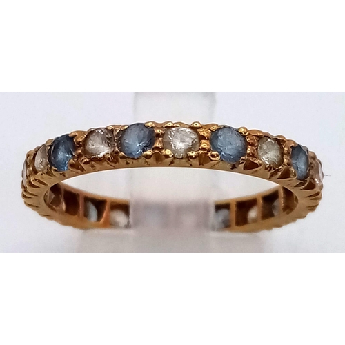 410 - AN 18K GOLD FULL ETERNITY RING WITH ATTRACTIVE BLUE AND WHITE STONES.  2.6gms  size Q