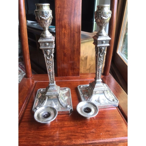 134 - A pair of early George V sterling solid silver mounted candlesticks, each with filled square base ha... 