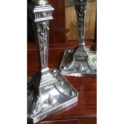 134 - A pair of early George V sterling solid silver mounted candlesticks, each with filled square base ha... 