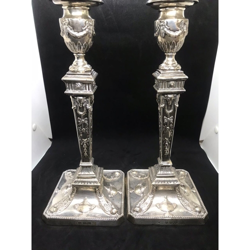 134 - A pair of early George V sterling solid silver mounted candlesticks, each with filled square base ha... 