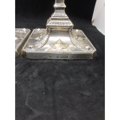 134 - A pair of early George V sterling solid silver mounted candlesticks, each with filled square base ha... 